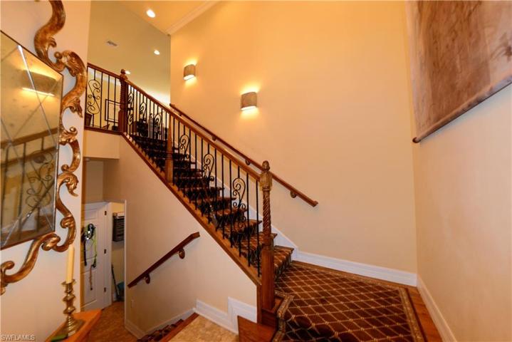 Entry Foyer with Volume Ceiling, Custom Crown Molding, Custom Tile Flooring, Upgraded Wood & Iron Banister and Elegant Wood Stairs with Custom Carpet Stair Tread Runner.