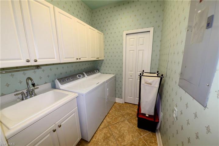 Large Laundry room features Ample wood cabinetry, Washer, Dryer, Laundry sink & Storage closet.