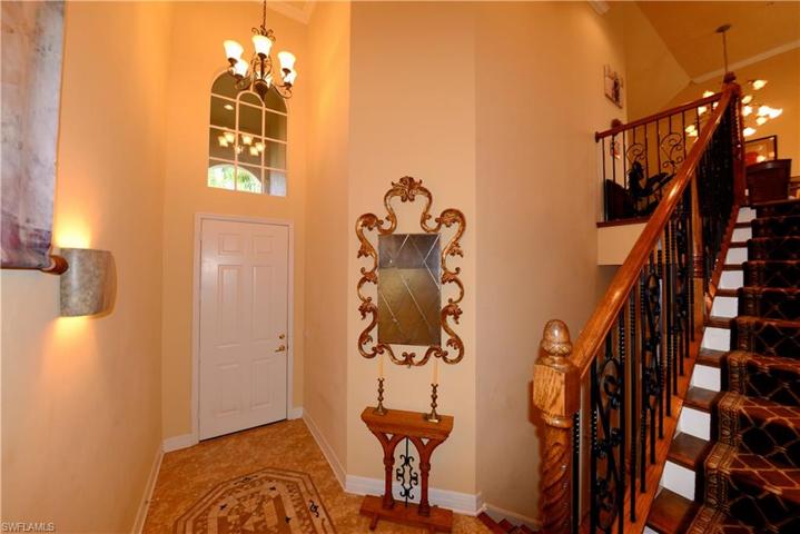 Entry Foyer with Volume Ceiling, Custom Crown Molding, Custom Tile Flooring, Upgraded Wood & Iron Banister and Elegant Wood Stairs with Custom Carpet Stair Tread Runner.