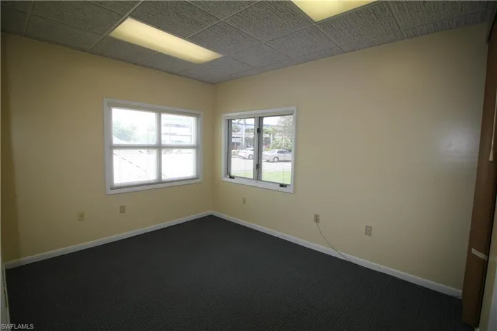 Empty room with dark carpet and a drop ceiling