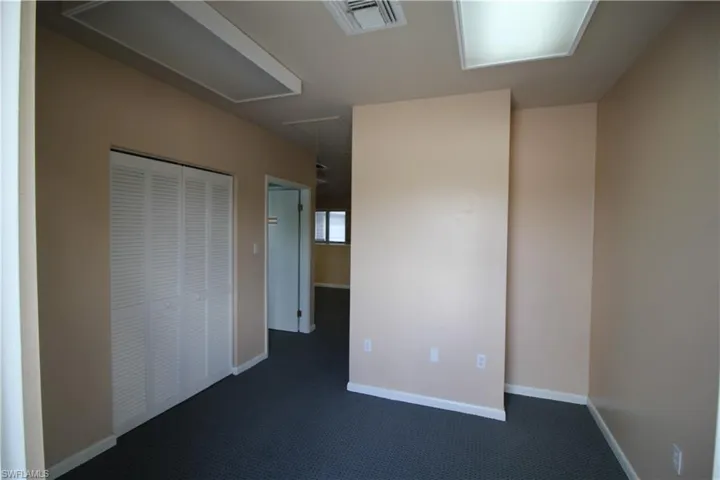 Unfurnished bedroom with dark carpet and a closet