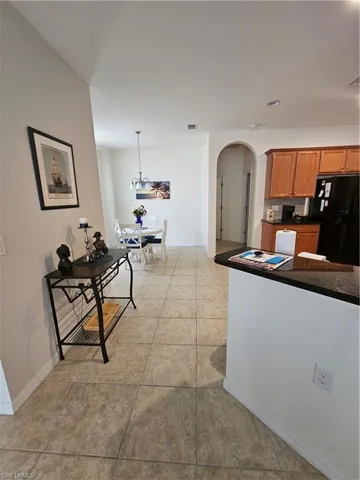 Kitchen featuring light tile floors, pendant lighting, and fridge
