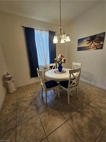 Dining area featuring dark tile flooring and an inviting chandelier