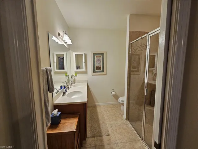 Bathroom featuring vanity, walk in shower, tile patterned floors, and toilet
