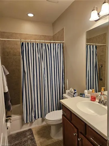 Full bathroom with tile patterned flooring, vanity, toilet, and shower / tub combo with curtain