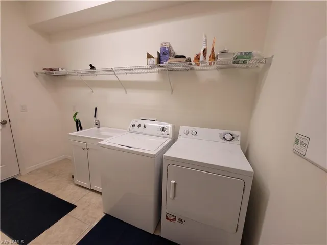 Laundry room with sink, washer and dryer, and light tile floors