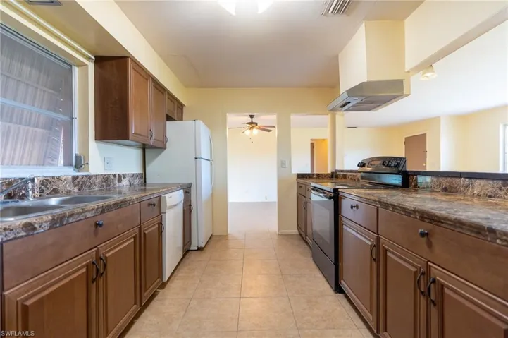 Kitchen featuring wood-finish cabinetry, tile flooring, and a double basin sink