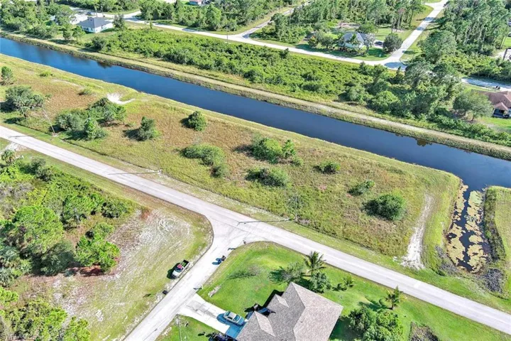 Aerial view of property and surrounding area with a large body of water and a tree filled landscape