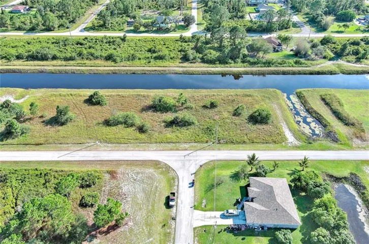 Aerial view of property and surrounding area featuring a large body of water and a tree filled landscape
