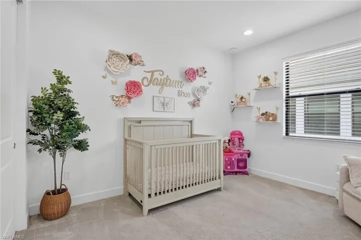 Bedroom with light colored carpet, a crib, and recessed lighting
