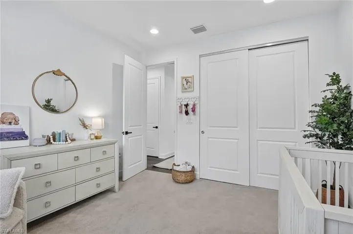 Bedroom featuring light carpet, a crib, a closet, and recessed lighting