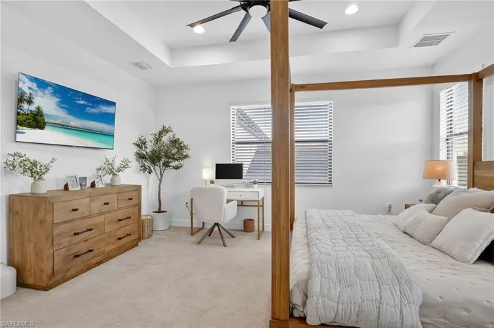 Bedroom with an office area, a tray ceiling, carpet flooring, a ceiling fan, and recessed lighting