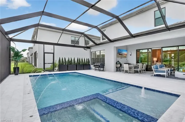 View of pool featuring a pool with connected hot tub, a patio, glass enclosure, a sunroom, and outdoor dining space
