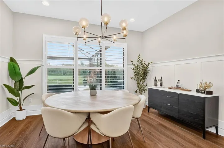 Dining area featuring wood finished floors, a chandelier, a decorative wall, and wainscoting