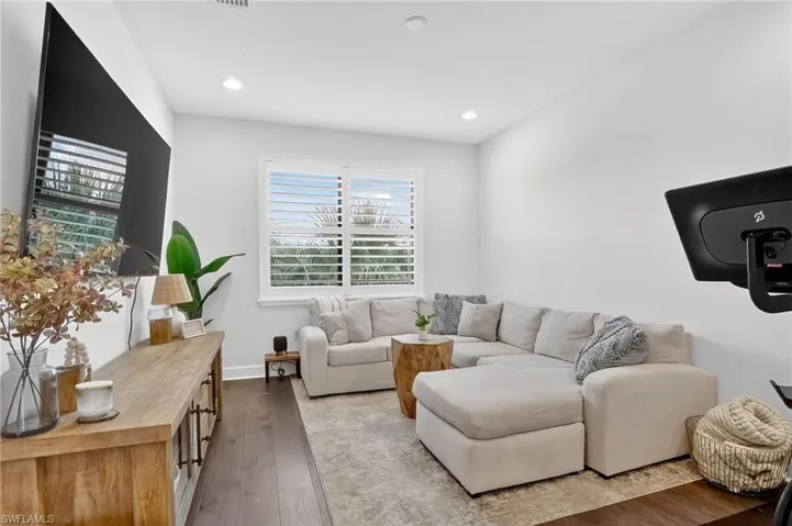Living area with dark wood-type flooring and recessed lighting
