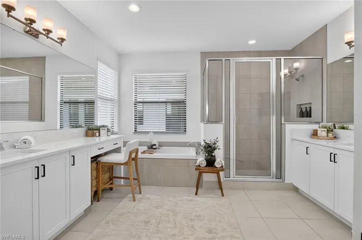 Full bath with a stall shower, two vanities, a garden tub, and recessed lighting