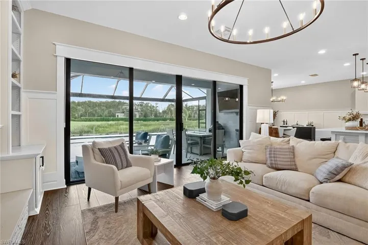 Living room featuring a decorative wall, wood finished floors, wainscoting, recessed lighting, and a chandelier