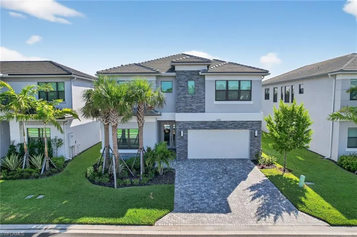 View of front of property featuring stone siding, a front lawn, and stucco siding