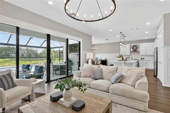 Living room with recessed lighting, dark wood finished floors, a sunroom, a chandelier, and wainscoting