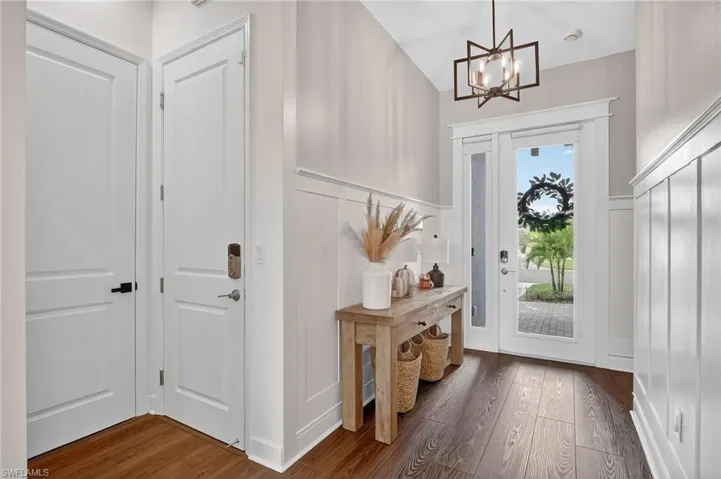 Doorway featuring wood finished floors, a chandelier, and a decorative wall