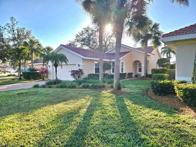 Mediterranean / spanish home featuring a garage and a front lawn
