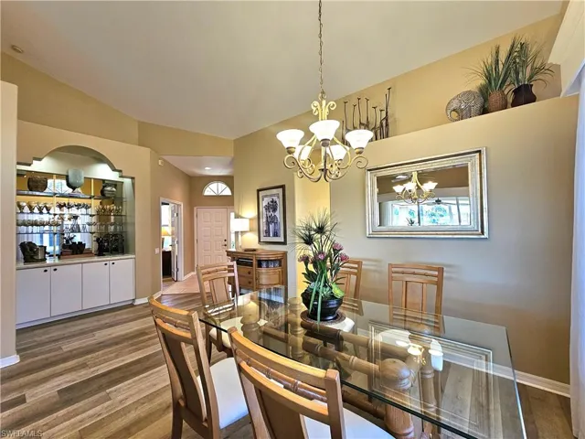 Dining space with hardwood / wood-style flooring, lofted ceiling, and a chandelier
