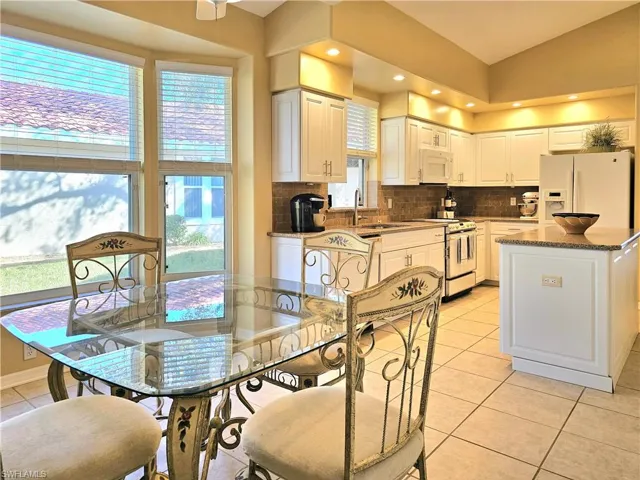 Kitchen with sink, light tile patterned floors, white appliances, a center island, and white cabinets