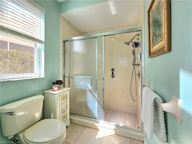Bathroom featuring walk in shower, tile patterned floors, and toilet