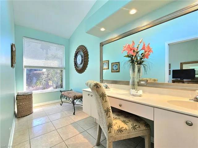 Bathroom featuring tile patterned flooring, vanity, and vaulted ceiling
