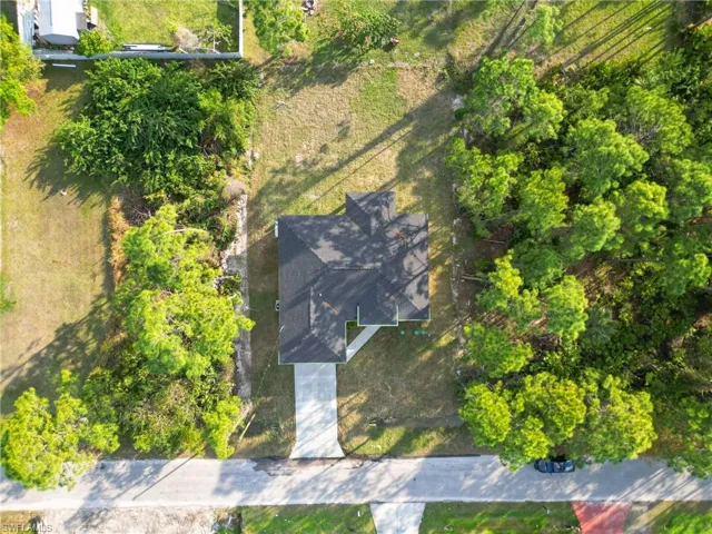 Single-story residence with a dark shingled roof, concrete driveway, and surrounding natural landscaping