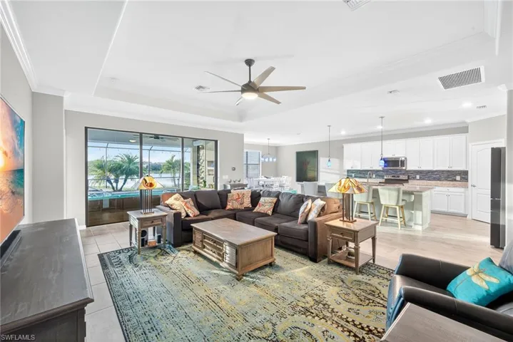 Living room with ornamental molding, a raised ceiling, and a ceiling fan
