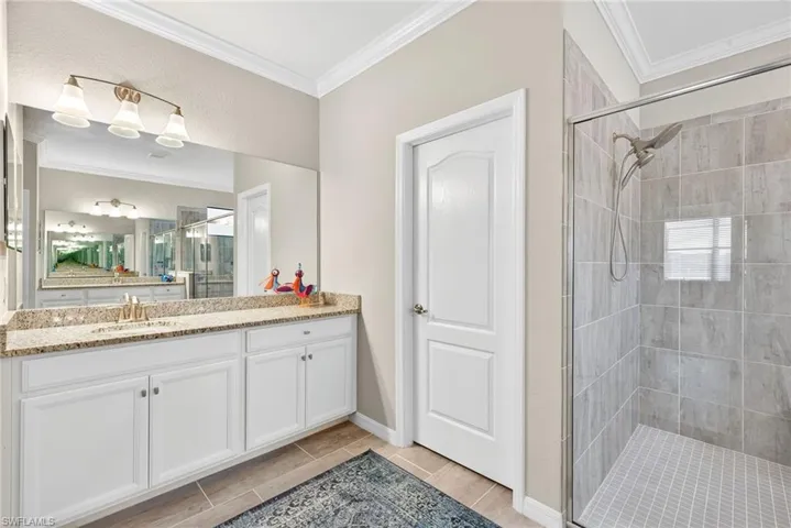 Full bath featuring crown molding, vanity, a stall shower, and wood finish floors
