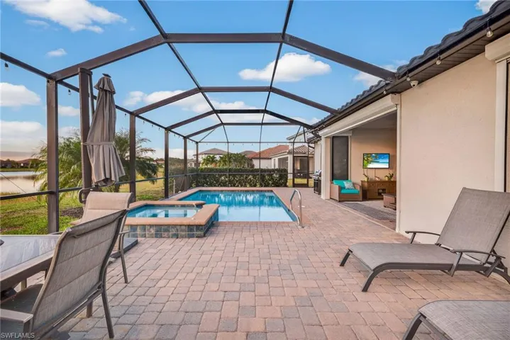 View of pool with a sunroom, a patio, glass enclosure, and a pool with connected hot tub