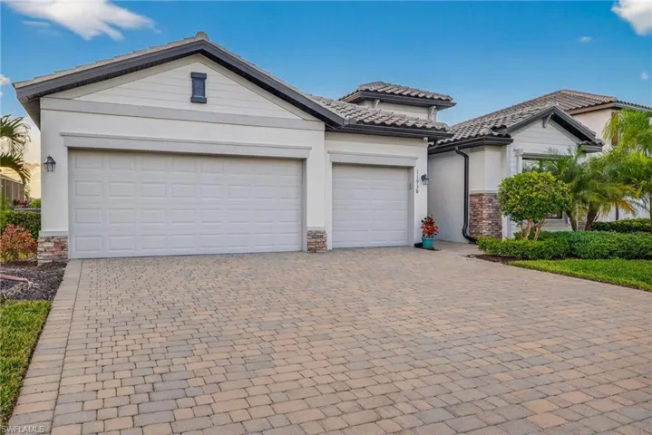 View of front of house with decorative driveway, stone siding, and stucco siding
