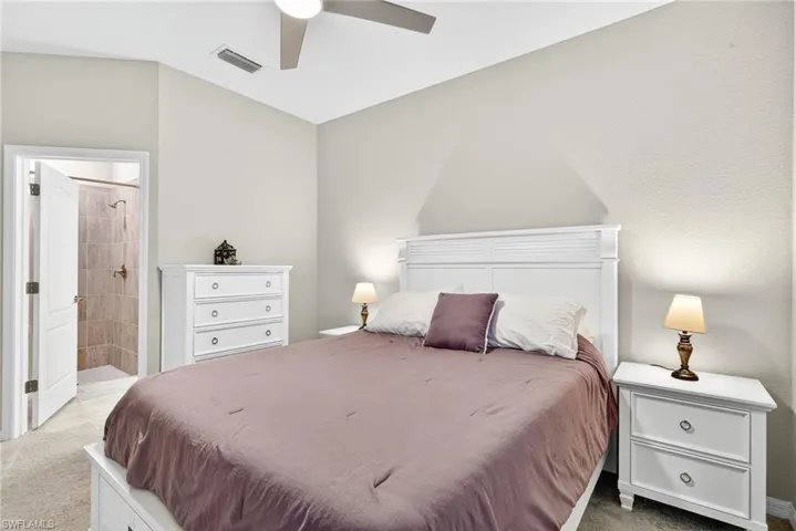 Carpeted bedroom featuring ensuite bath and ceiling fan