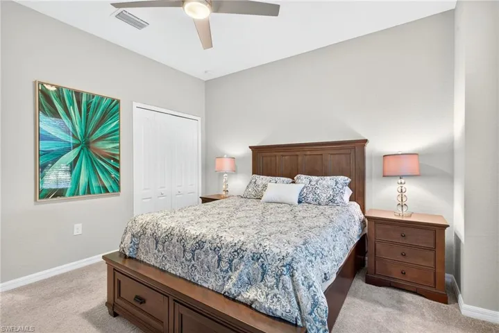 Bedroom with light colored carpet, a closet, and a ceiling fan