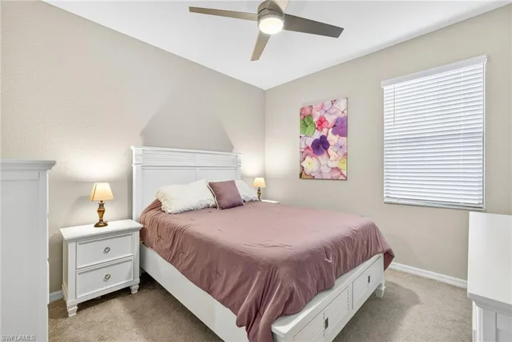 Bedroom featuring light colored carpet, a ceiling fan, and a textured wall