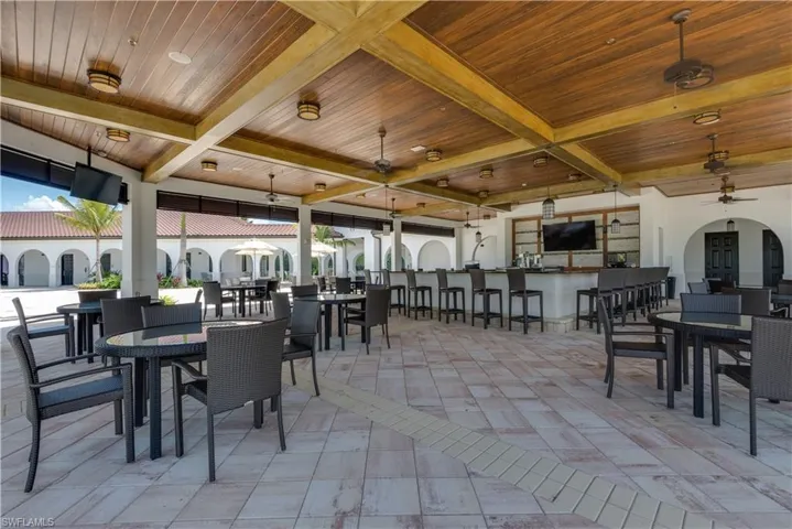View of patio with outdoor dining space, a bar, and a ceiling fan