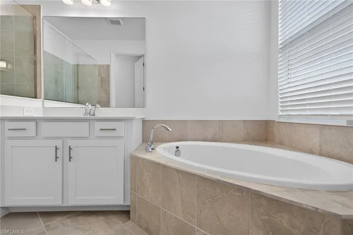 Primary Bathroom with vanity, a garden tub, light tile patterned floors, and a tile shower