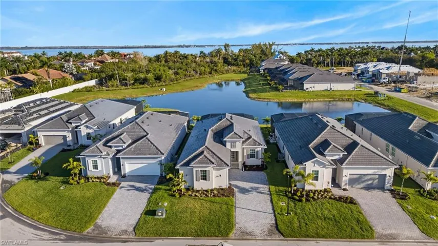 Aerial perspective of suburban area featuring a large body of water and a tree filled landscape