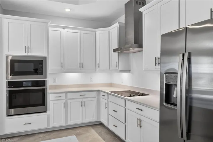 Kitchen with stainless steel appliances, white cabinets, light tile patterned floors, and recessed lighting