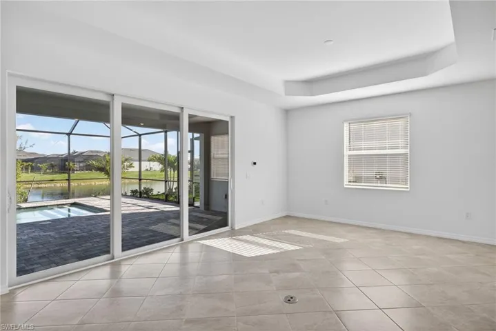 Family Room featuring a sunroom, a water view, a tray ceiling, a residential view, and light tile patterned flooring