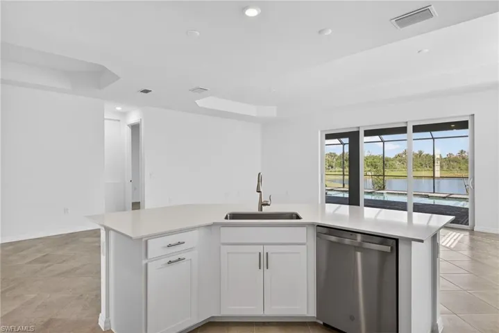 Kitchen featuring a kitchen island with sink, dishwasher, white cabinets, recessed lighting, and open floor plan