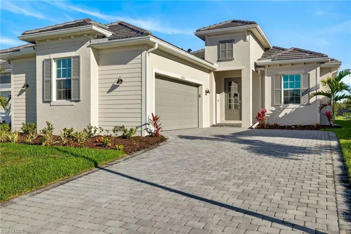 View of front of house featuring decorative driveway, an attached garage, stucco siding, and a tiled roof