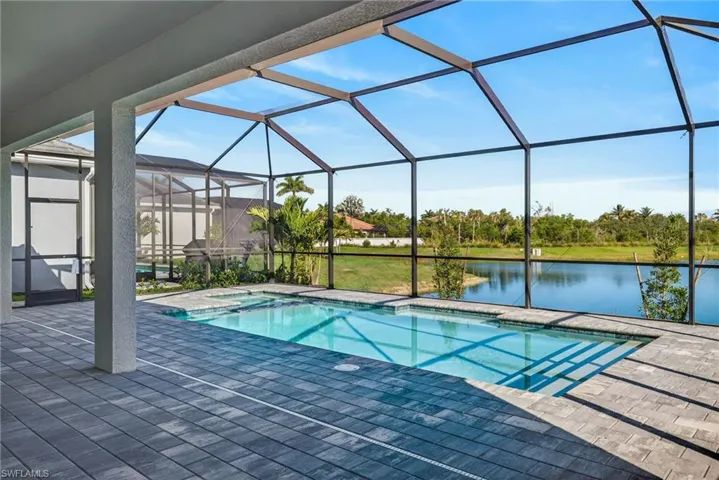 Combined pool / hot tub with a sunroom, a water view, a patio area, and a lanai
