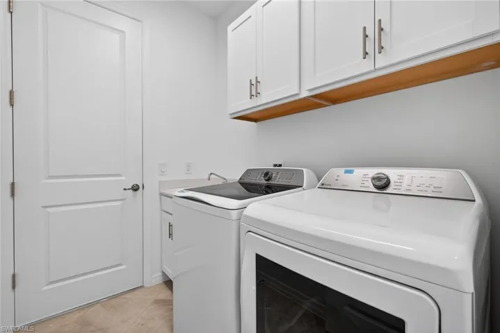 Laundry room with cabinet space, washer and clothes dryer, and light tile patterned floors