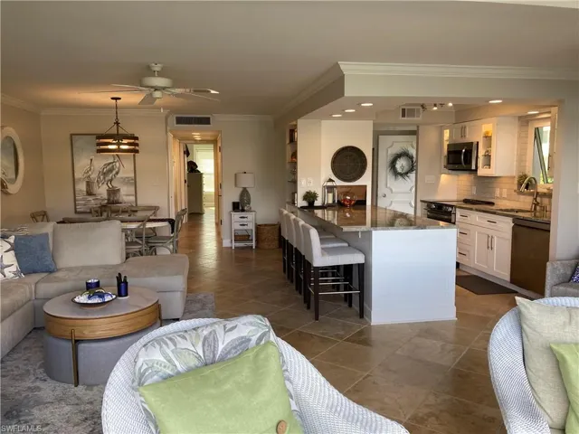 Living room with ornamental molding, ceiling fan, and dark tile patterned flooring