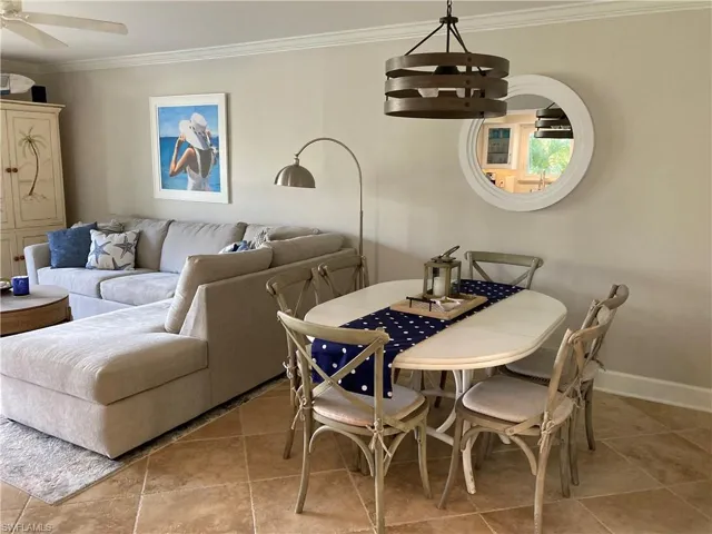 Dining space with ornamental molding, light tile patterned flooring, and a ceiling fan