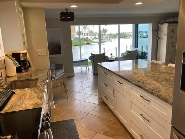 Kitchen with white cabinets, dark stone counters, electric range oven, a water view, and recessed lighting