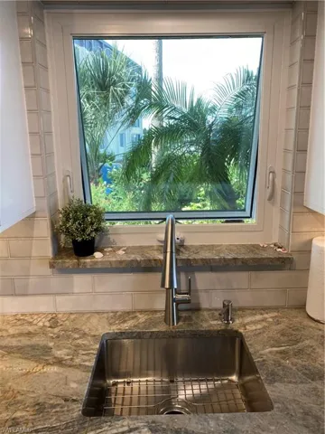 Kitchen view of a sink and dark stone counters